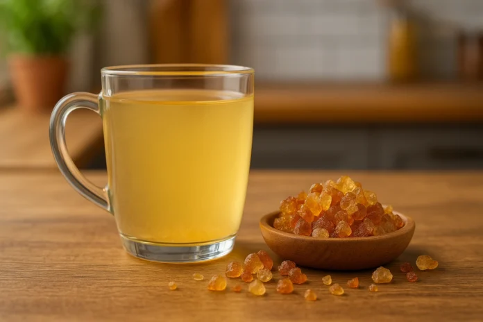 الصمغ العربي الهشاب كوب منقوع الصمغ العربي الهشاب مع حبيبات الصمغ على طاولة خشبية داخل مطبخ طبيعي.