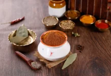 بهارات برياني اللحم الأصلية (الحيدرابادية الفاخرة) بهارات برياني اللحم في وعاء خزفي أبيض محاطة بتوابل هندية متنوعة على طاولة خشبية.